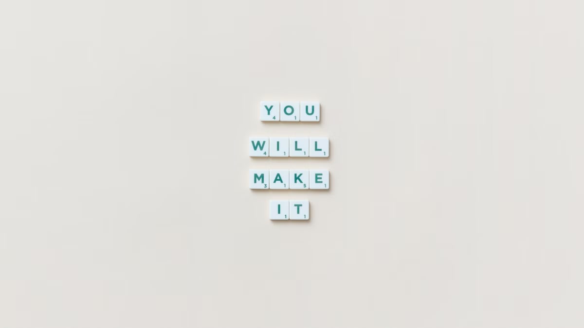 Motivational phrase 'You Will Make It' made from Scrabble tiles on a neutral background.